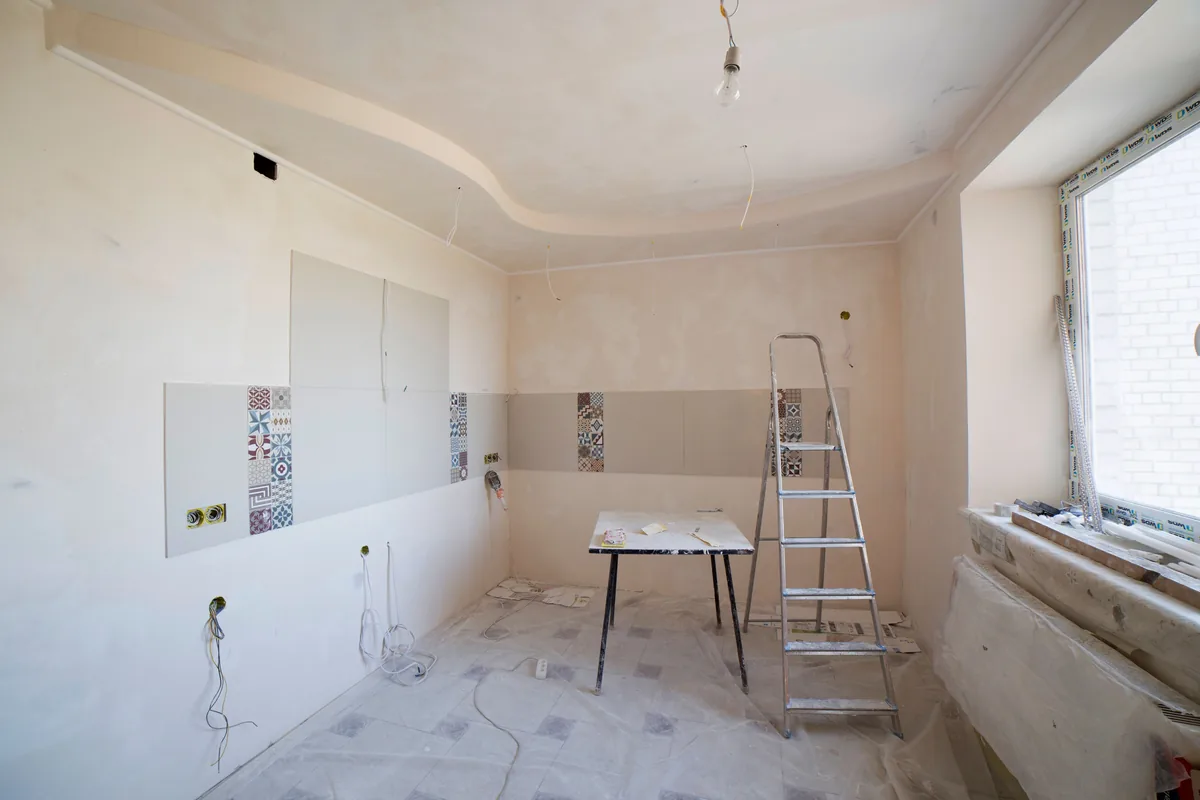Interior room under renovation with ladder, unfinished walls, and work surfaces