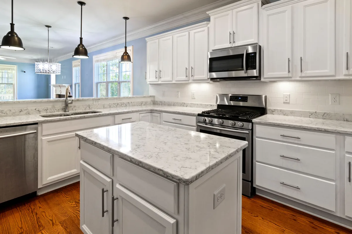 Bright kitchen design inspiration with white cabinetry, stone counters, and pendant lighting